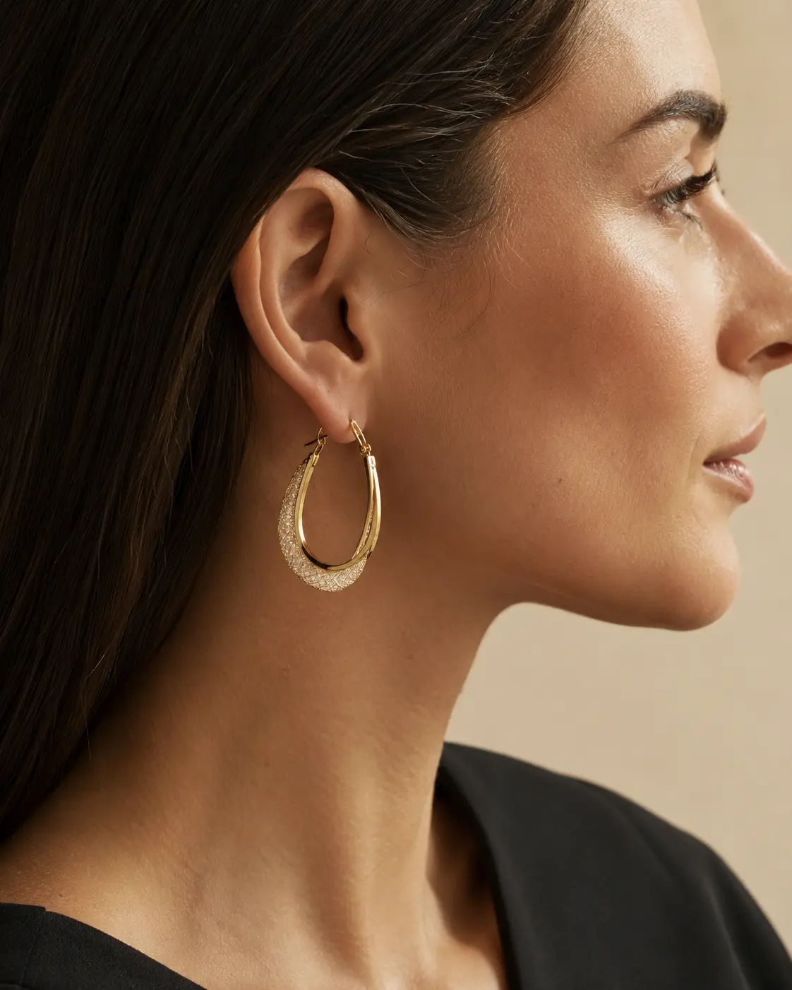 Model wearing sculptural crystal hoop earrings in an editorial setting.